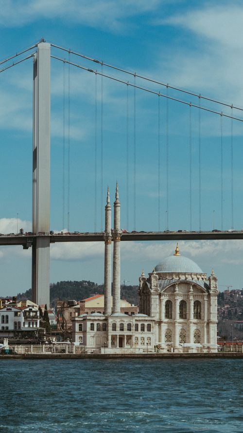 Free Stunning view of a bridge and mosque by the river with urban skyline in the background. Stock Photo