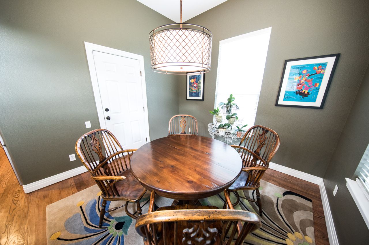 Wooden Windsor-style chairs around a round wooden dining table in a small dining nook