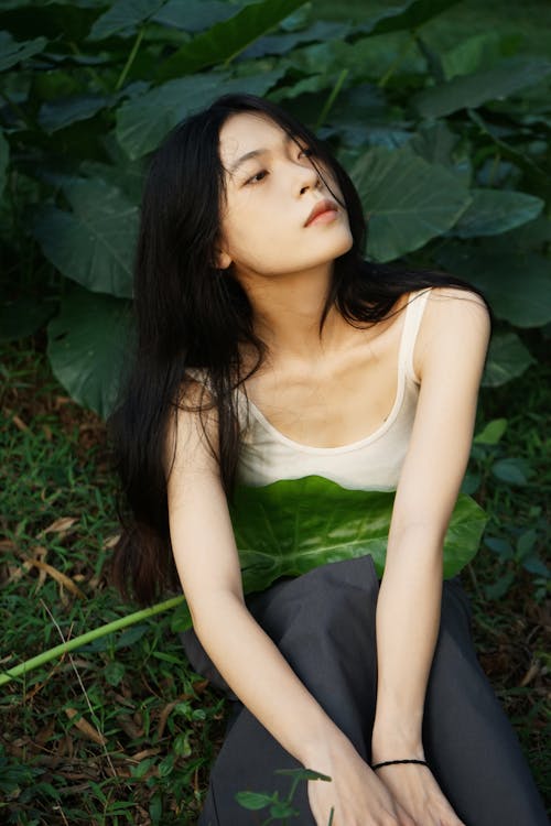 Young Woman Sitting next to Green Plants 