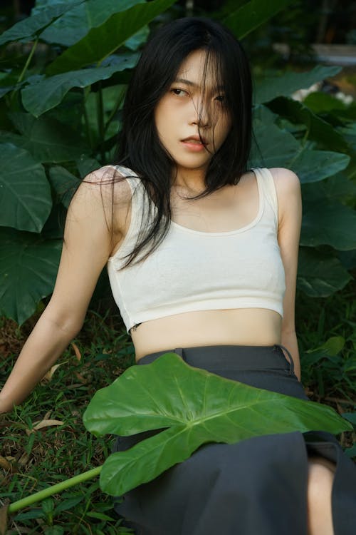 Young Woman Sitting next to Green Plants 