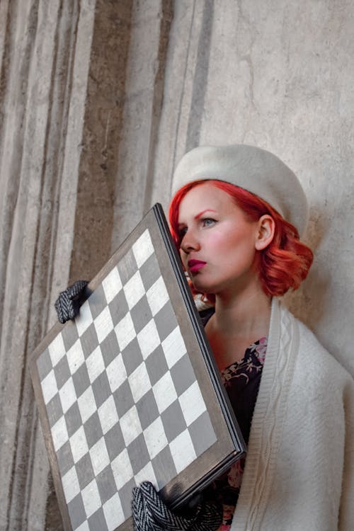 Redhead Woman in Beret Holding Chess Board