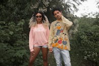 一对穿着休闲服装的时尚情侣，自信地在郁郁葱葱的绿植环绕中摆出姿势