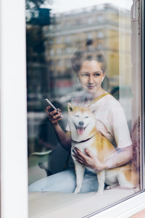 A woman holding a dog in front of a window
