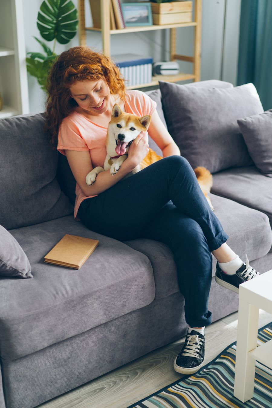 A sitter on the sofa with a dog in the client's living room