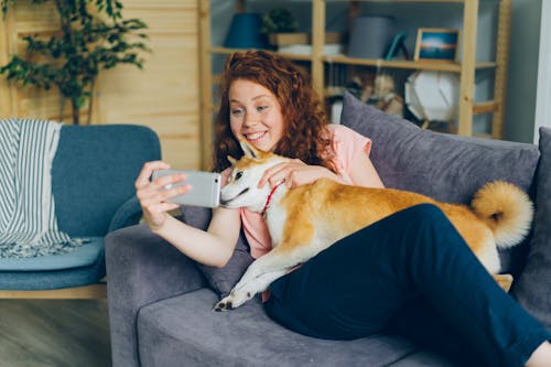 A woman is sitting on a couch with her dog