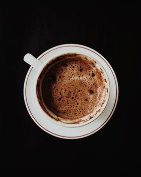 Elegant top-down view of a steaming coffee cup showcasing rich crema against a dark backdrop.