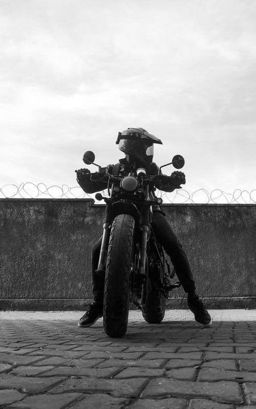 Free Bold black and white photo of a motorcyclist against a concrete wall. Stock Photo