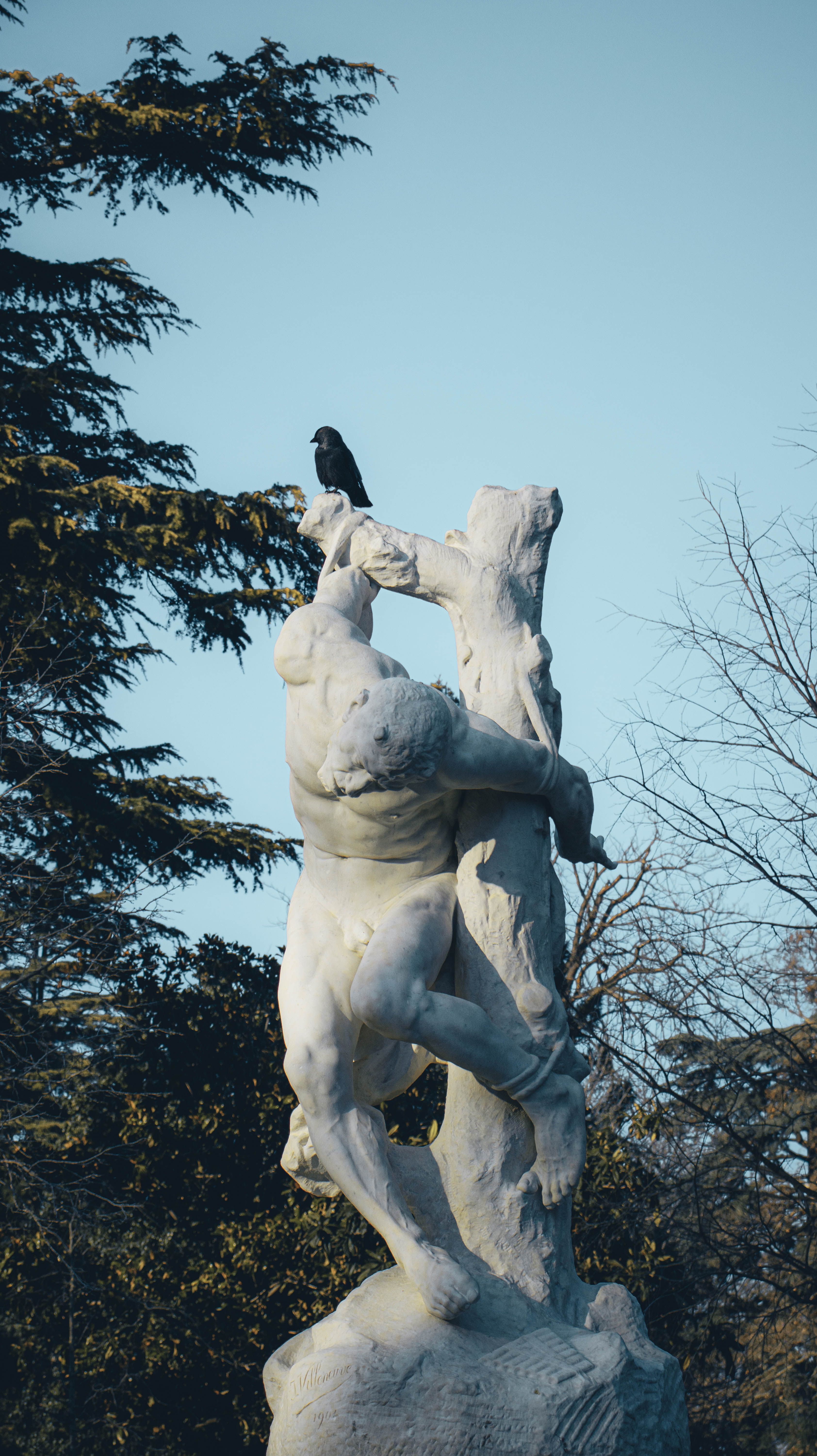 Statue in Montpellier's park with a bird perched on top on a sunny day.