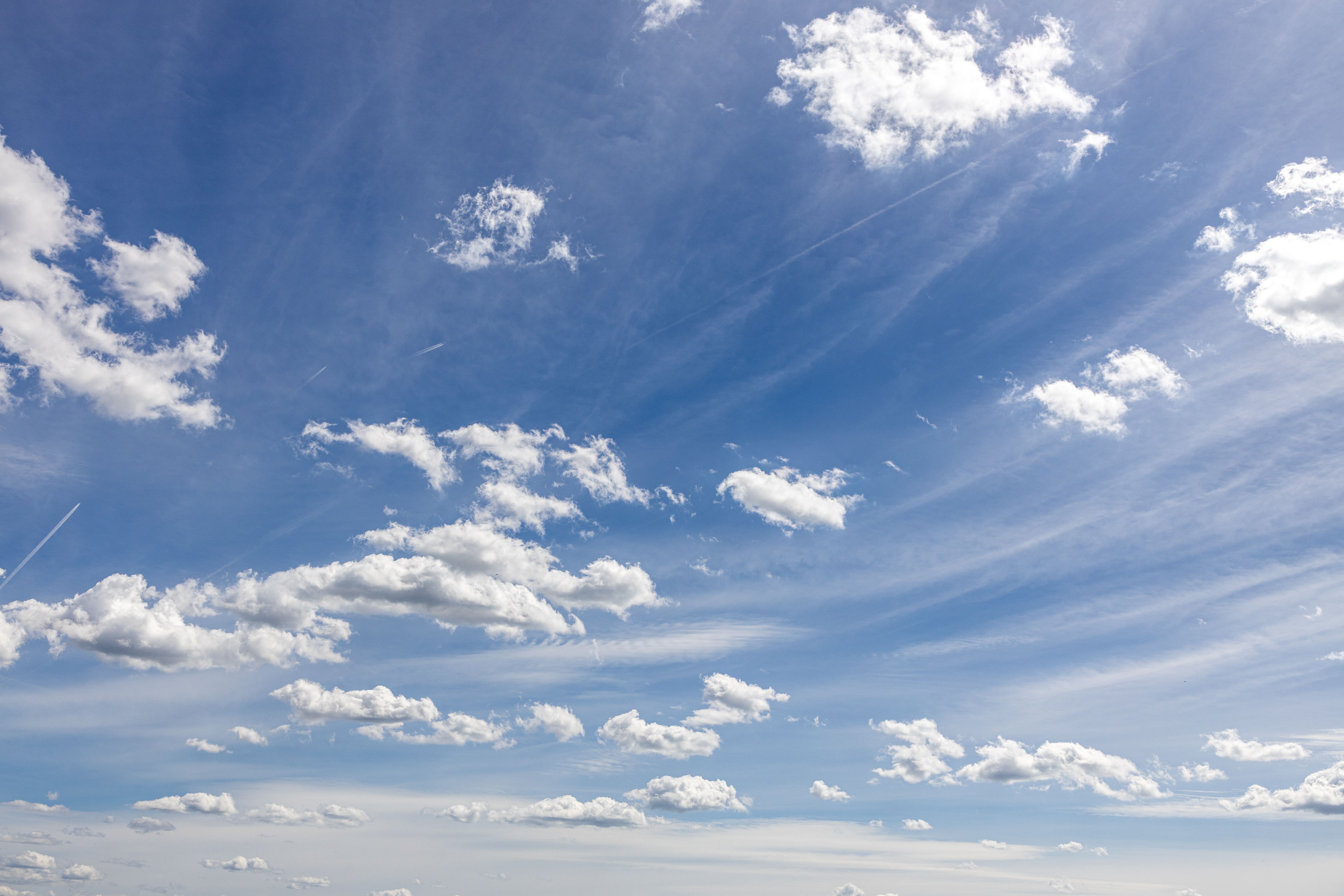 A blue sky with white clouds and a plane flying · Free Stock Photo