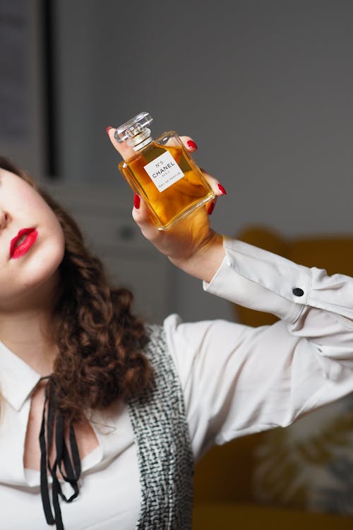 A woman holding up a bottle of perfume