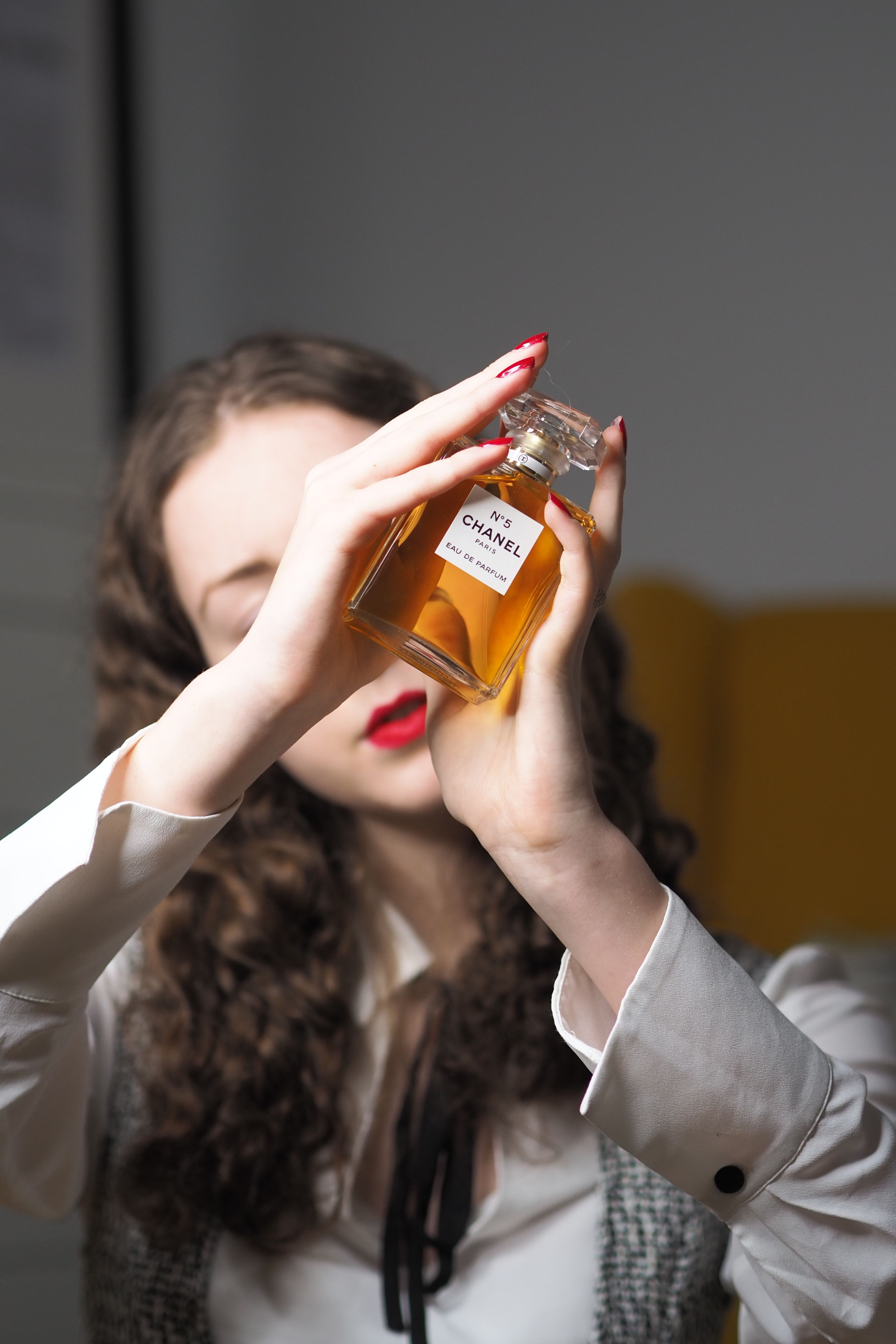 Mulher estilosa segurando a garrafa de Chanel N°5, destacando a elegância e o luxo.