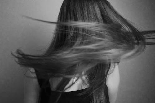 A black and white photo of a woman with her hair blowing in the wind