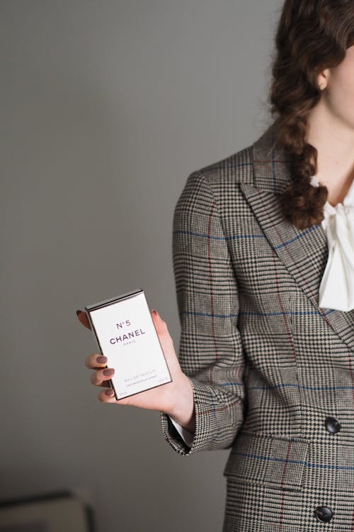 A woman in a suit holding a box of perfume