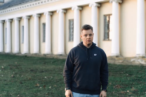 A man in a black hoodie standing in front of a building