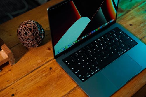 Free Top view of a laptop on a wooden desk with a decorative wicker sphere beside it. Stock Photo