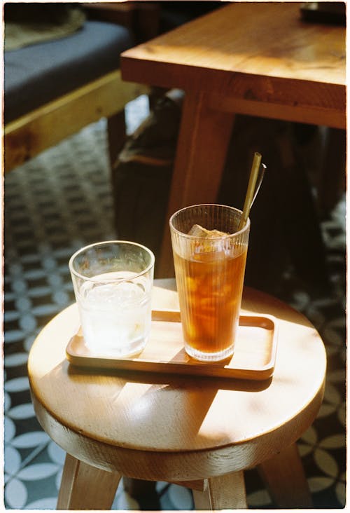 A glass of water and a glass of iced tea on a wooden table