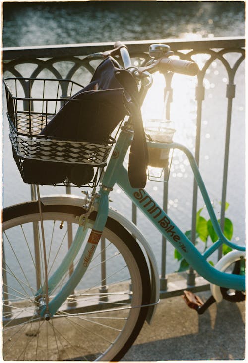 A bicycle with basket on the handle bar next to a river