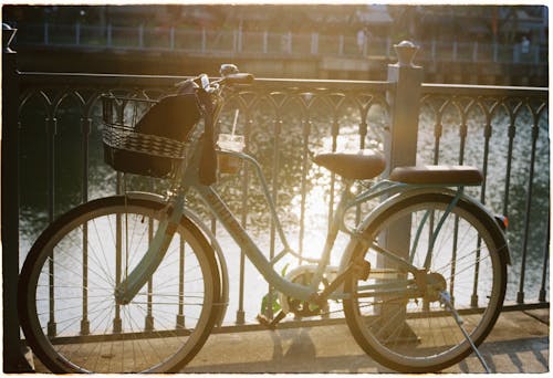 A bicycle parked near a railing by a river