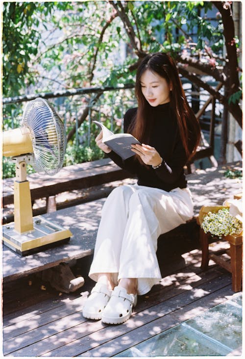 A woman sitting on a bench reading a book