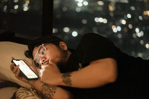 A man laying in bed with his phone