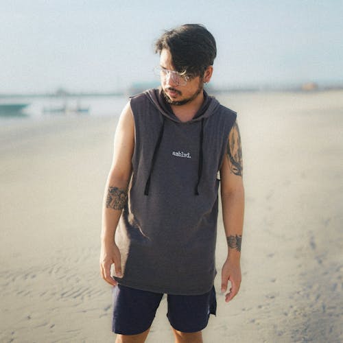 Portrait of Man in Tank Top and with Tattoos Standing on Beach