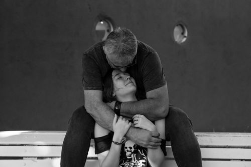Free A loving couple embraces warmly on a bench in a black and white composition. Stock Photo