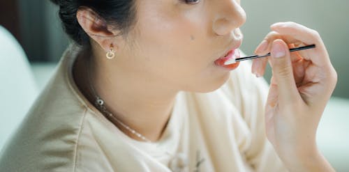 A woman applying lipstick on her lips