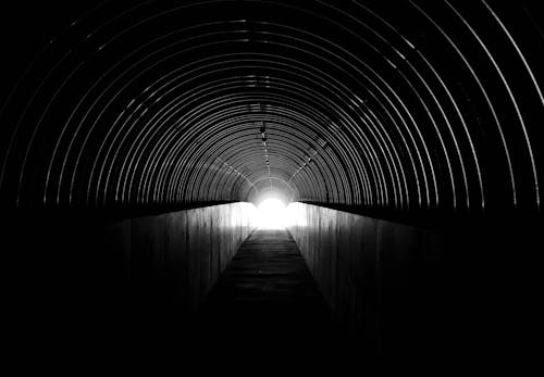 A black and white photo of a tunnel with a light