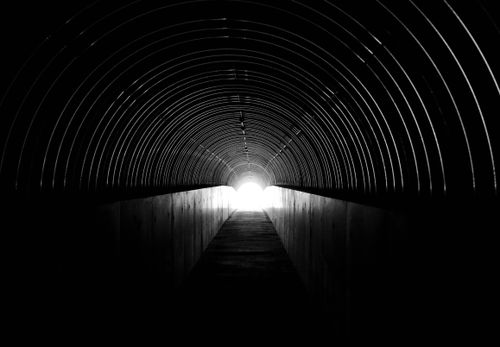 Free A striking black and white photo of a tunnel with a bright light at the end. Stock Photo