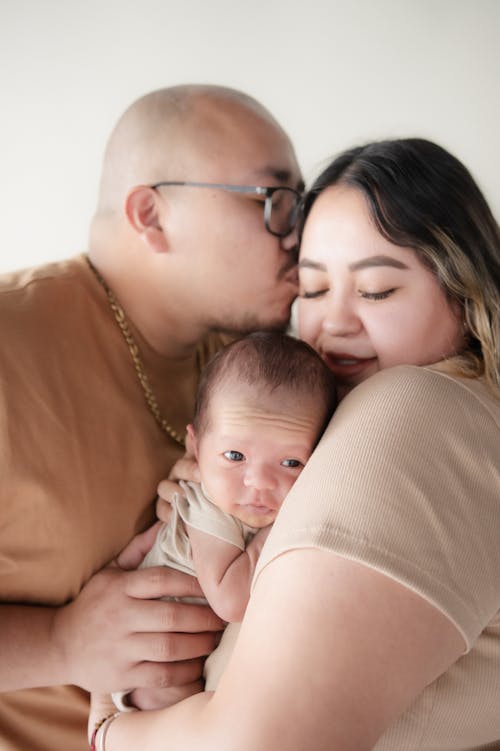 A man and woman kiss their baby while holding him