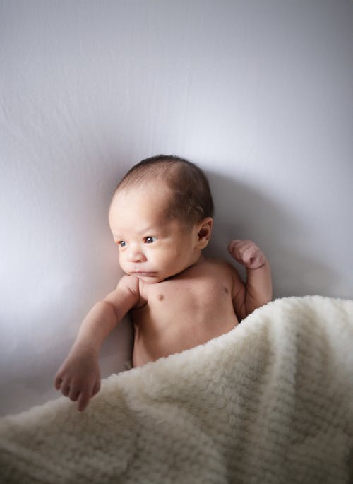 A baby is laying on a blanket in a studio