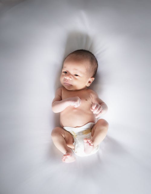 A baby is laying on a white blanket