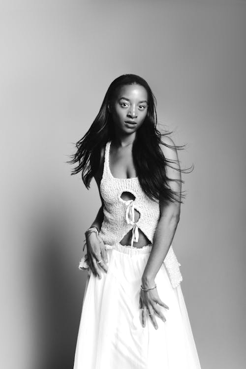 A woman in a white dress posing for a black and white photo