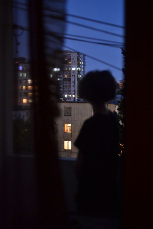 Free Silhouette of a woman gazing out at city buildings during evening twilight. Stock Photo