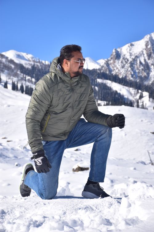 Free A man kneels in snow, surrounded by the stunning Himalayan mountains in India. Stock Photo