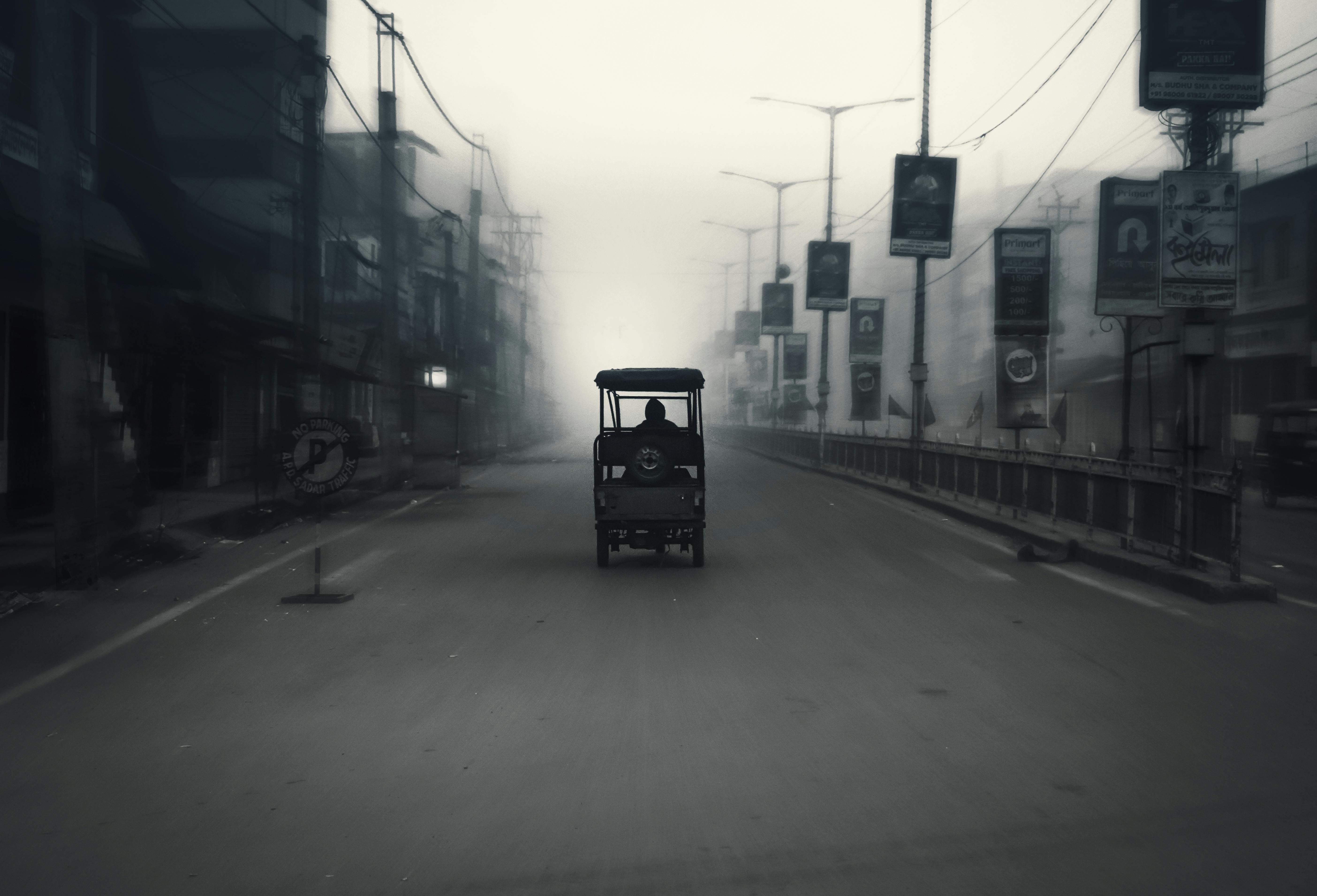 Rickshaw traveling down a foggy urban street, capturing the essence of city life.