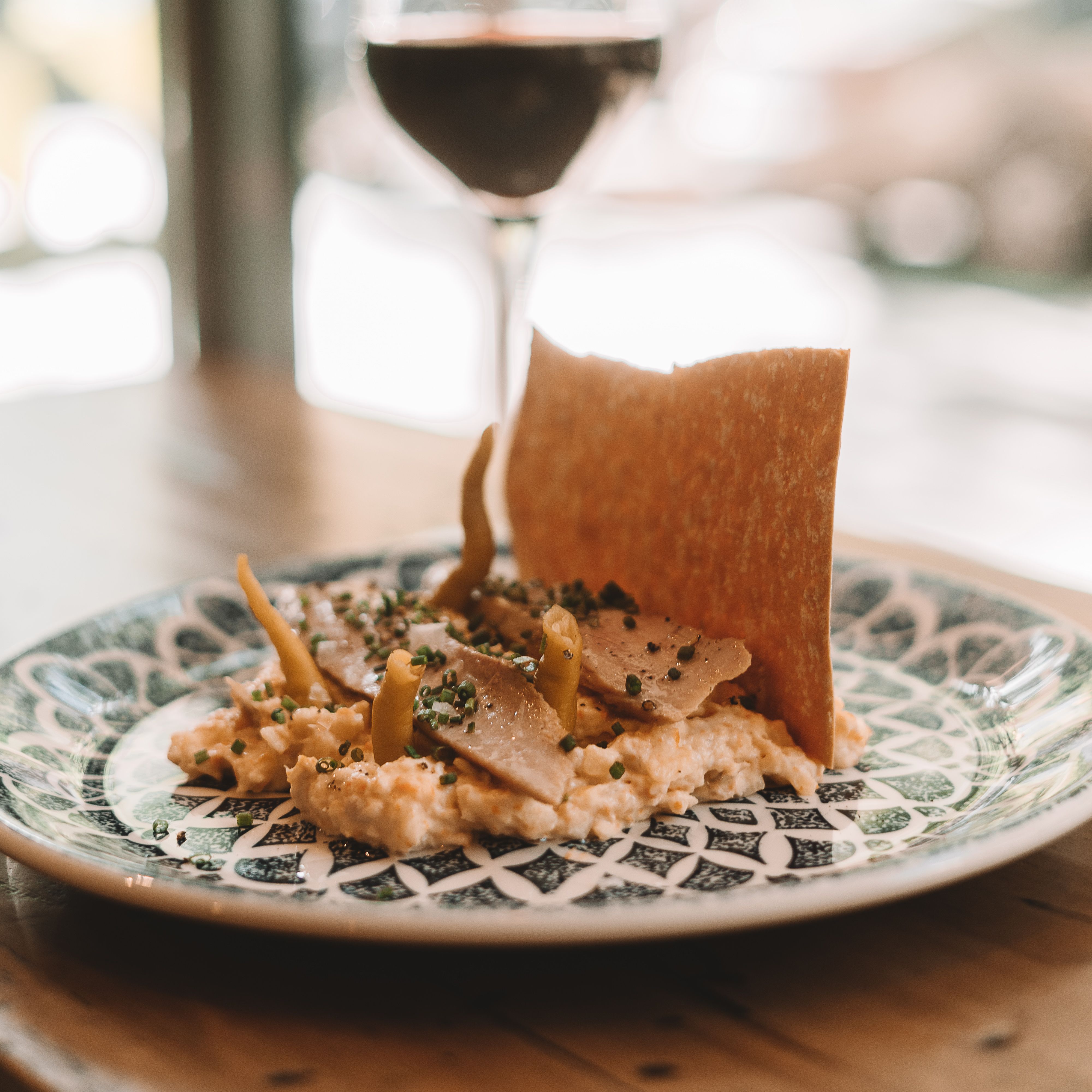 Elegant gourmet potato salad served in a Madrid cafe, paired with a glass of red wine.
