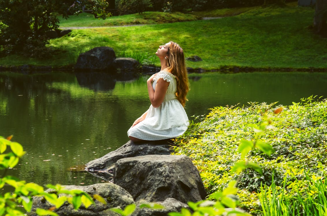 A girl sitting on a rock in a pond