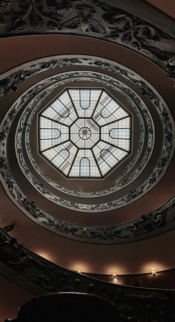 A mesmerizing view of the ornate spiral staircase and glass ceiling in Vatican City, showcasing intricate design and architecture.