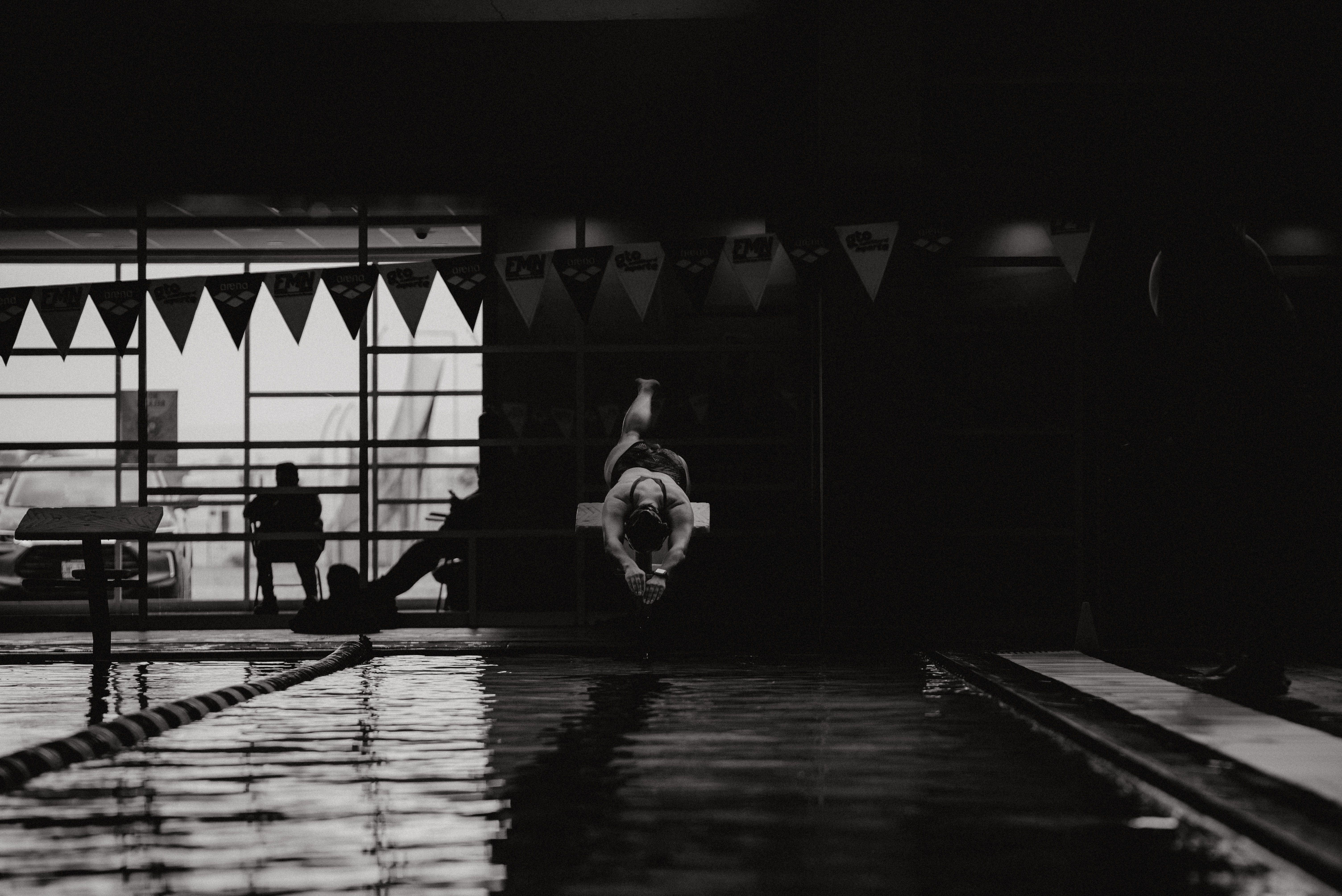 Ein Schwimmer springt in ein Hallenbad, was Bewegung und Geschicklichkeit zeigt.