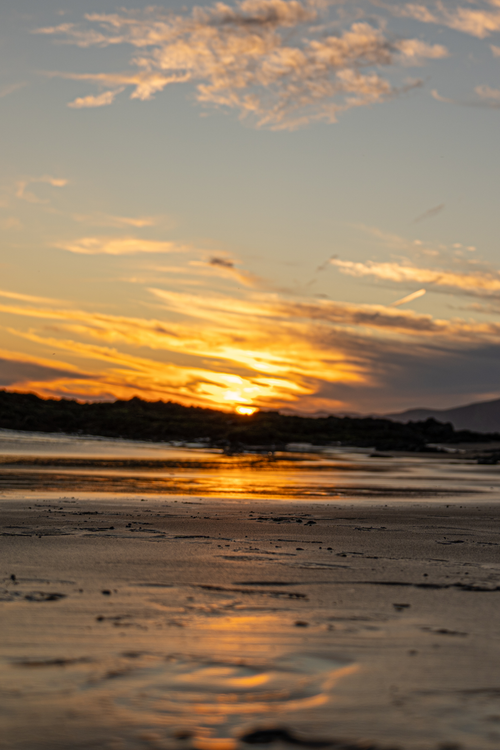 Free Capture of a beautiful sunset over a tranquil beach with dramatic clouds and golden reflections on the water. Stock Photo