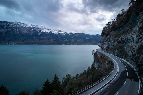 A road going over a mountain with a lake in the background