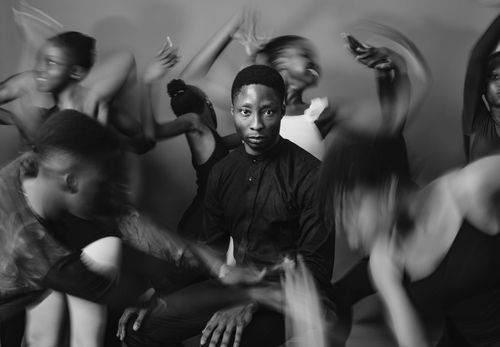 Free A striking black and white image of a man in motion, surrounded by dancing figures, exuding energy and style. Stock Photo