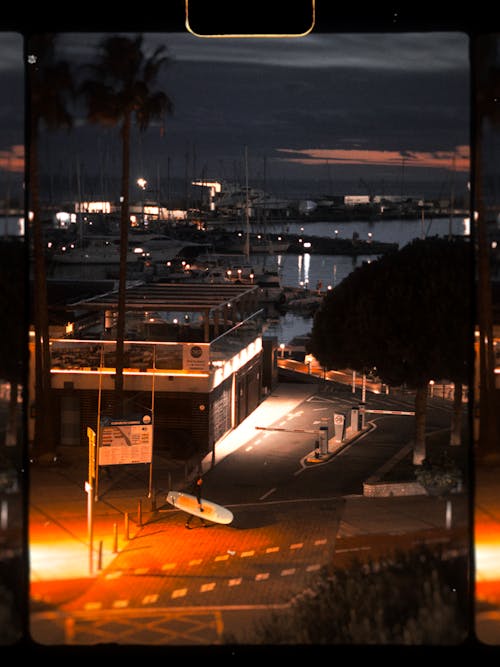 Man with Surfboard Crossing Street at Dusk