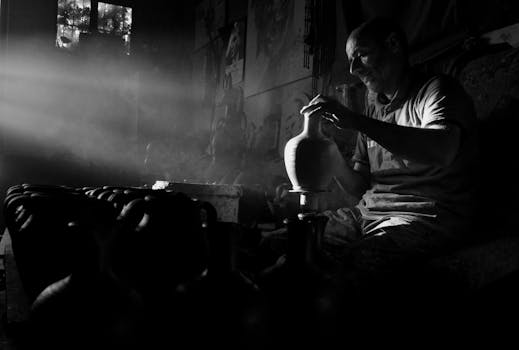 Black and white photo of a potter skillfully crafting ceramics in Avanos, Türkiye, with dramatic lighting.