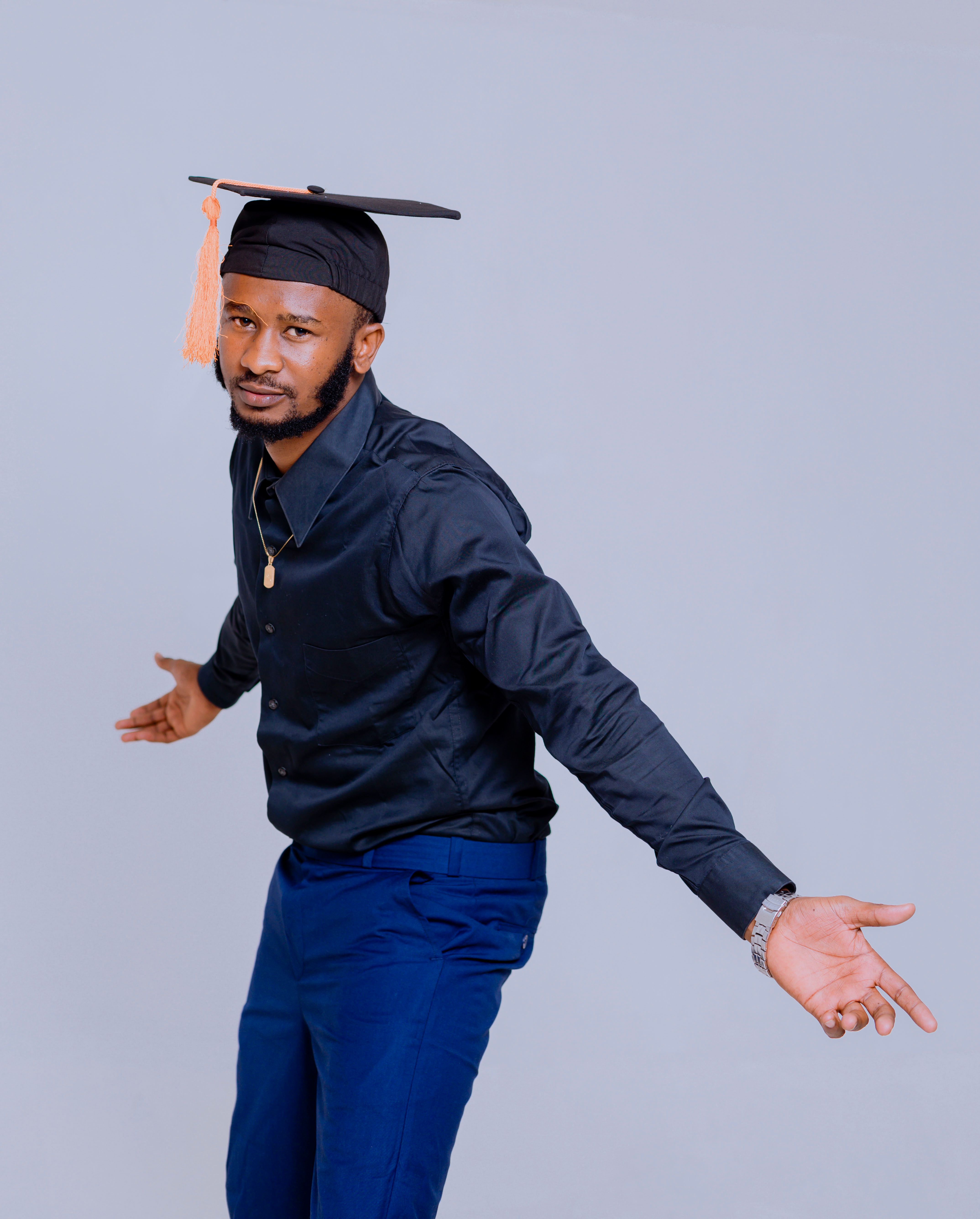 Young man in graduation cap posing confidently in studio setting.