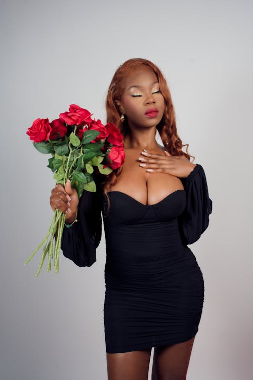 A woman in a black dress holding roses