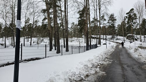 A snow covered road with a fence and a fence