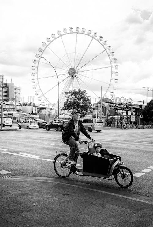 A man riding a bike with a ferris wheel in the background