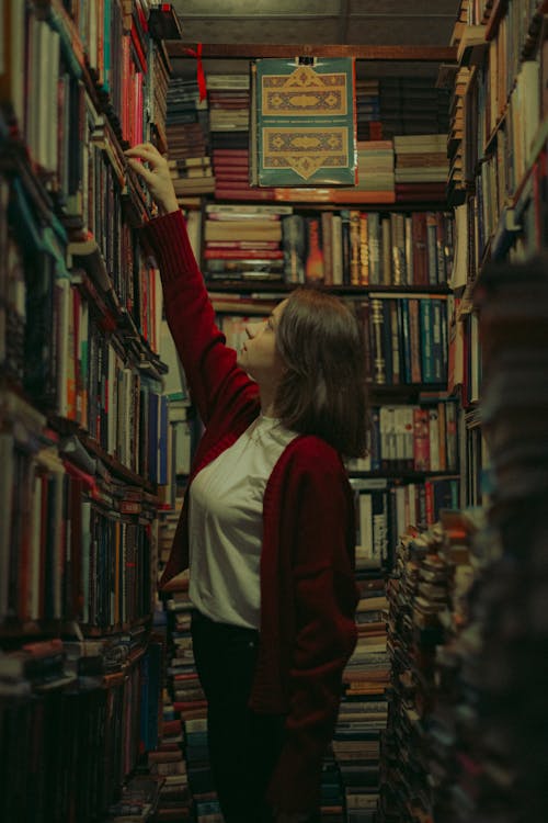 A woman reaching for books in a library